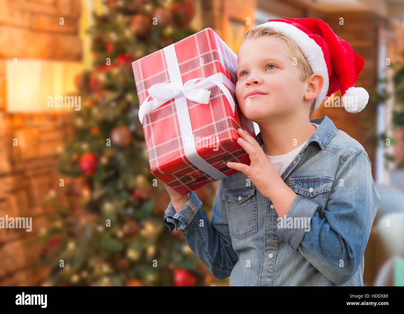 Curioso Joven vistiendo gorro de Papá Noel para celebrar la Navidad Regalo delante del árbol adornado. Foto de stock