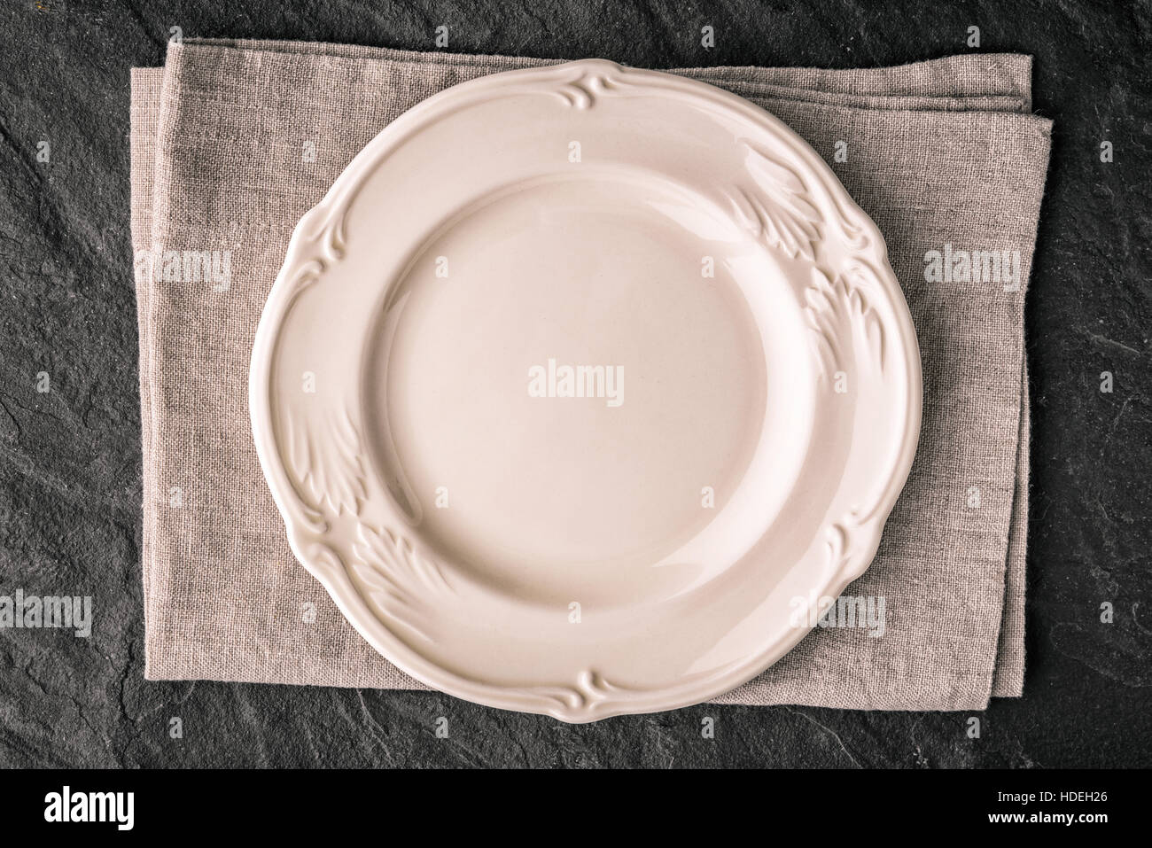 Placa de cerámica blanca en la oscuridad de la tabla de piedra vista superior Foto de stock