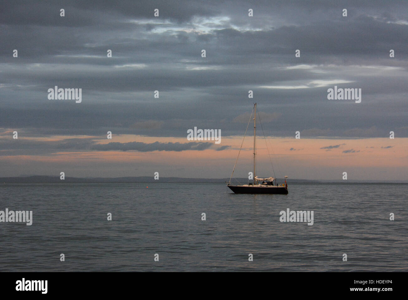 Un Yate anclado en una tranquila noche de verano con un tranquilo atardecer. Foto de stock