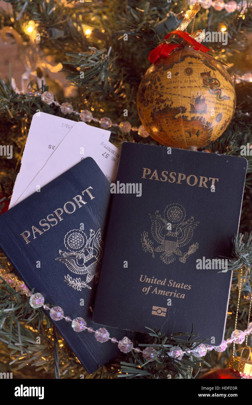 Pasaportes y tarjetas de embarque con un árbol de Navidad ornamento del mundo todos colgando de un árbol de Navidad Foto de stock