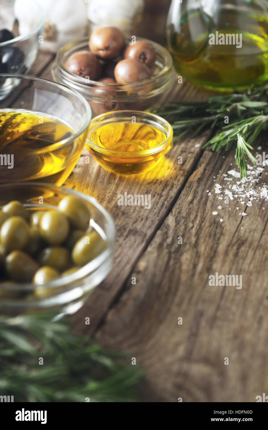 El aceite de oliva y las aceitunas en la mesa de madera vertical Foto de stock
