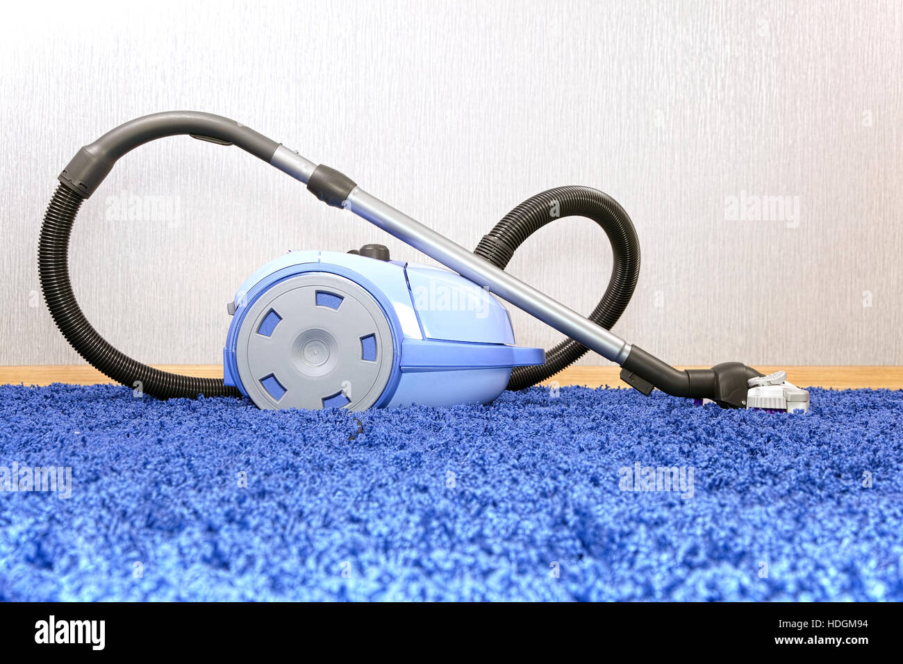Potente aspiradora de pie sobre una alfombra azul.