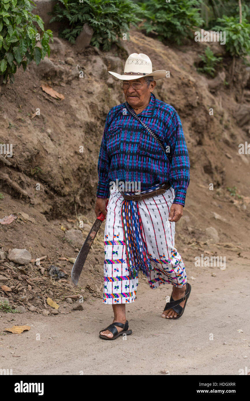 Un viejo agricultor maya vestida con un traje tradicional de San Pedro la  Laguna, Guatemala, camina a su pequeña granja parcela sobre un camino de  tierra, acrrying un machete Fotografía de stock -