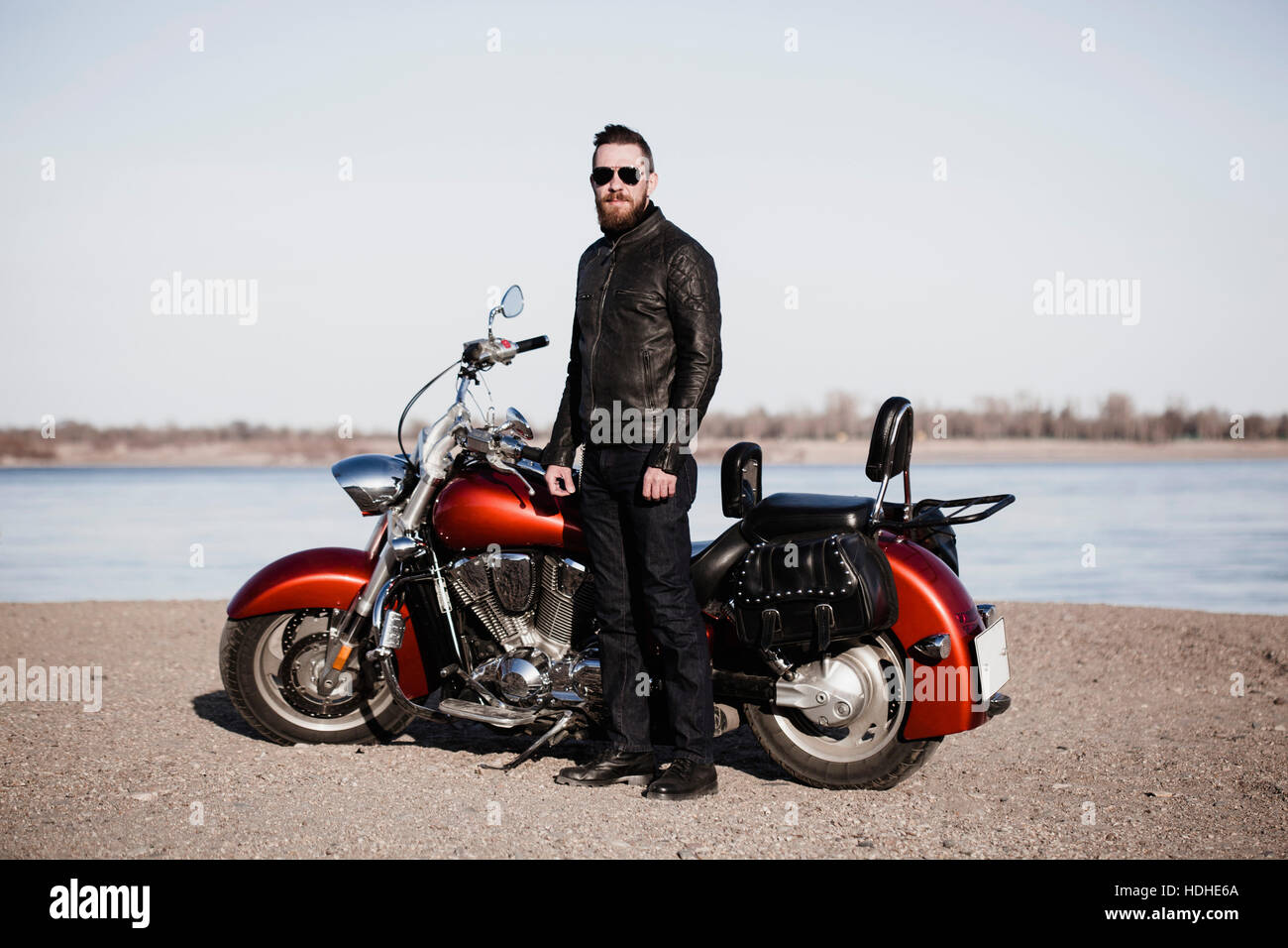 Retrato de longitud completa permanente biker por motocicleta en Lakeshore Foto de stock