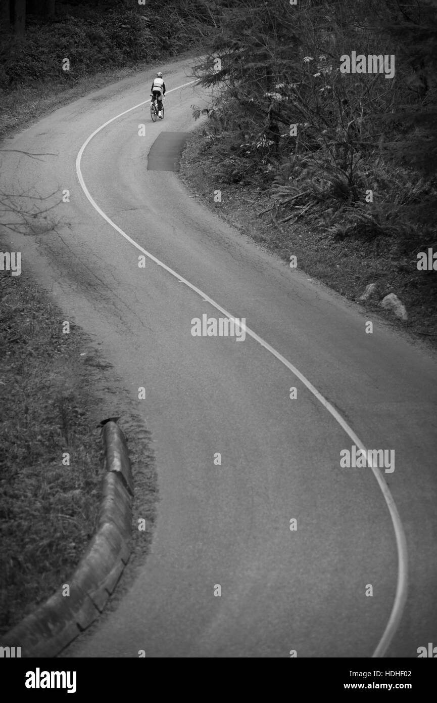Vista lejana del ciclista montando bicicleta en Country Road Foto de stock