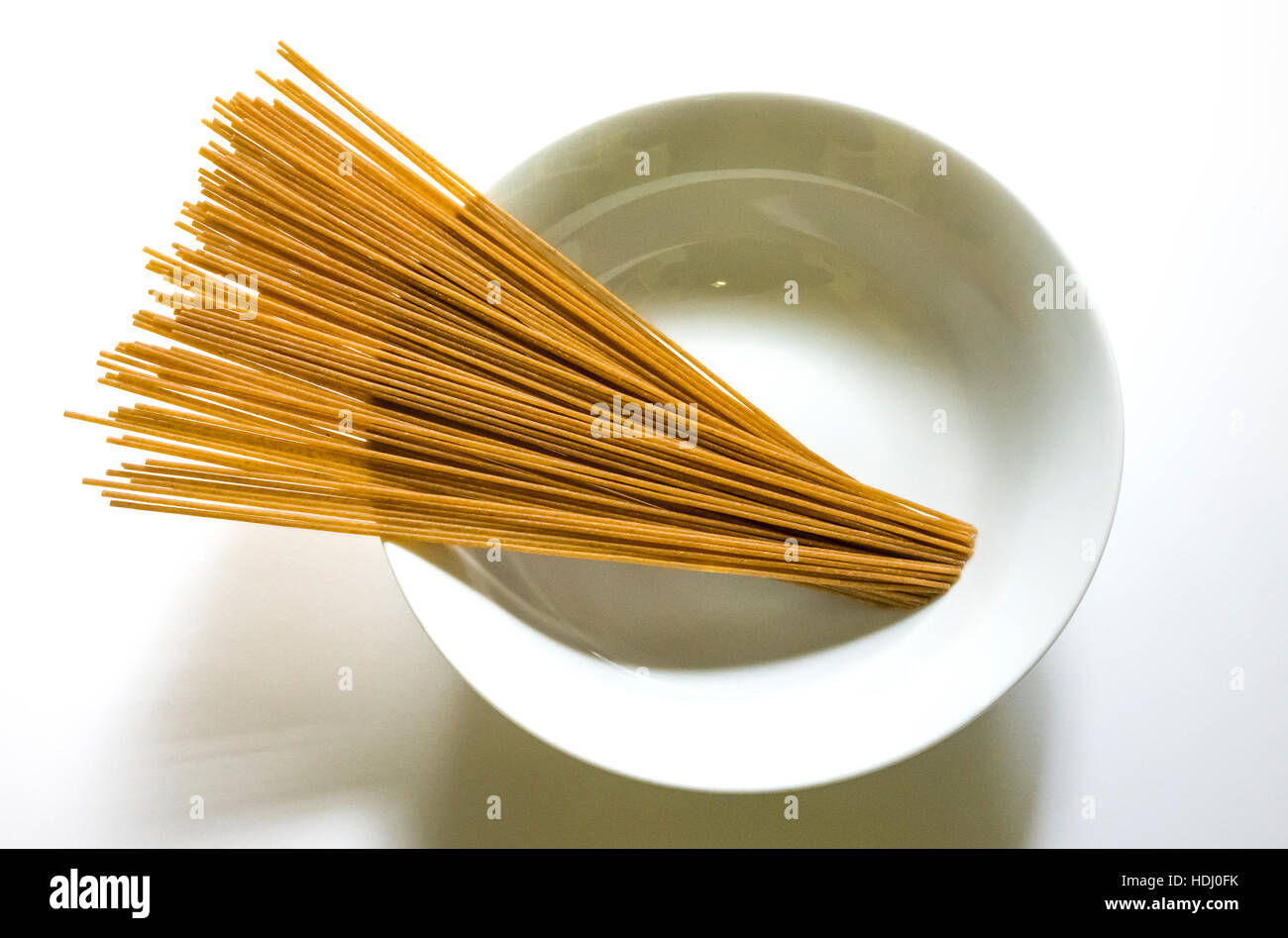 Sin cocer los espaguetis de trigo entero en un recipiente blanco Foto de stock
