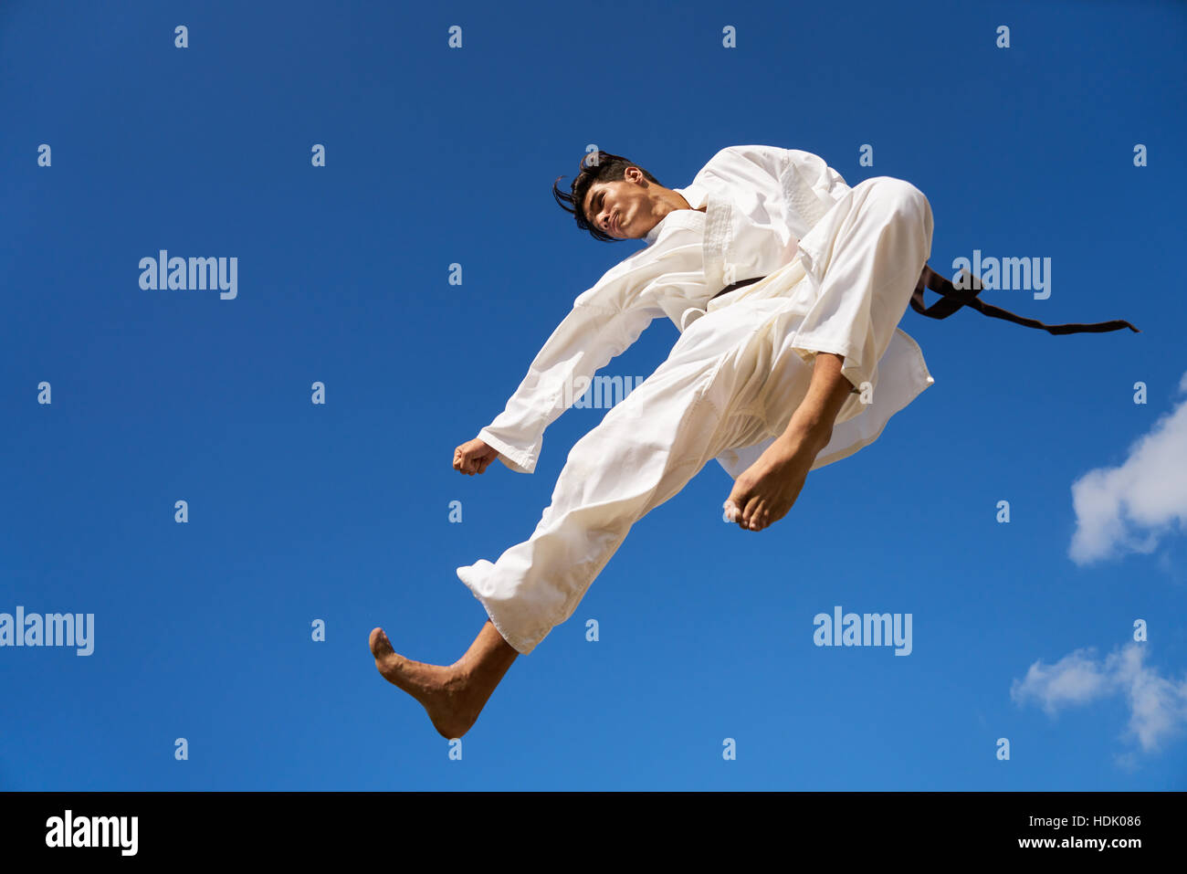 Los jóvenes, atleta, actividad deportiva, combatir y deportes extremos. Hombre hispano ejercer en karate y artes marciales tradicionales, saltando en mitad del aire en t Foto de stock