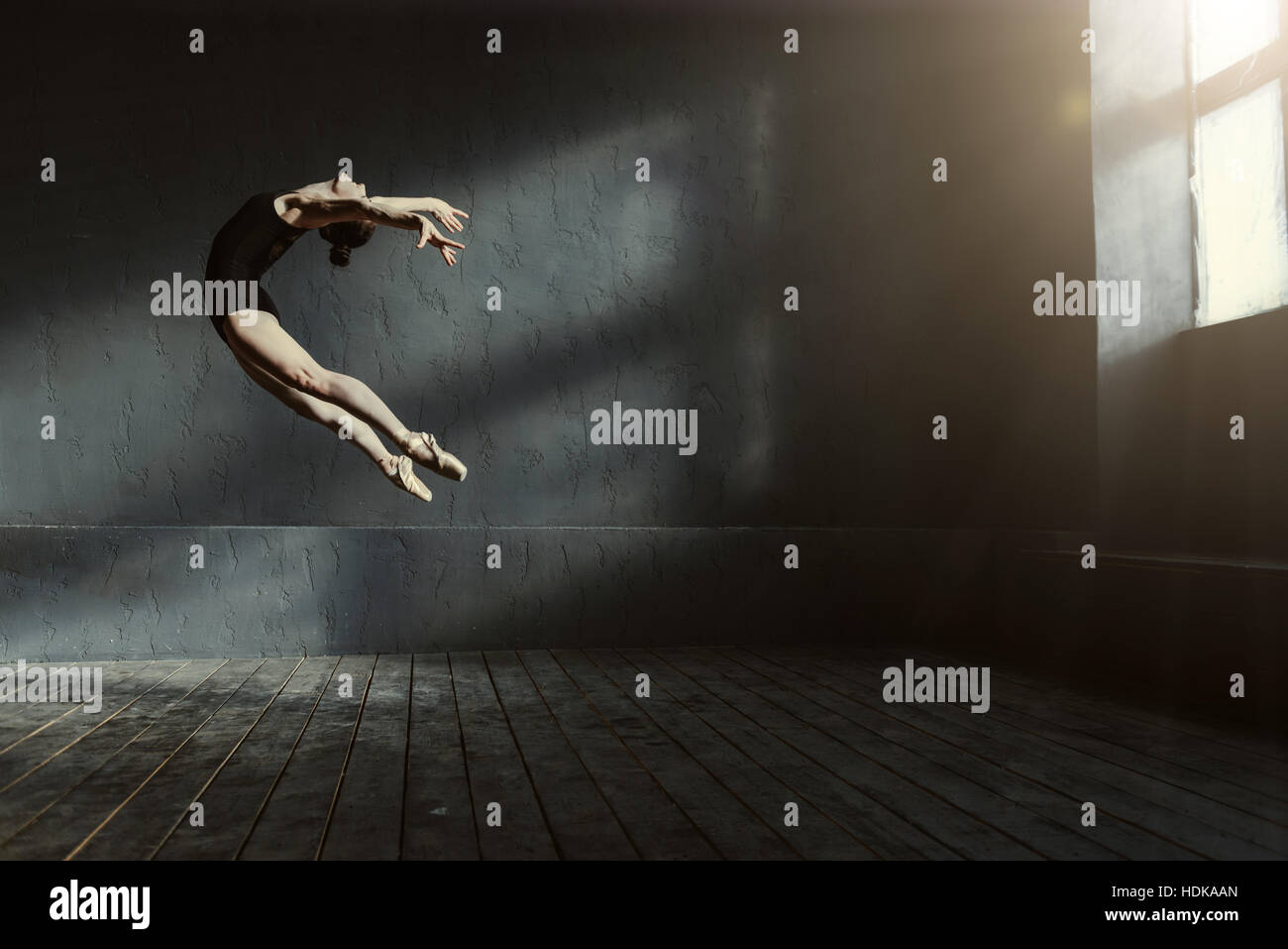 Bailarín de ballet profesional realiza en la oscuridad de la habitación iluminada Foto de stock