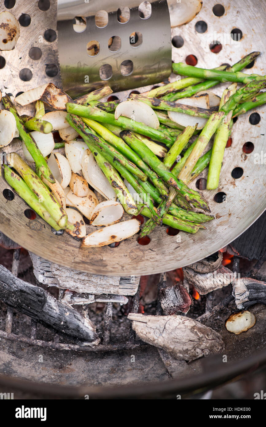 Los espárragos verdes de asar en cacerola en el carbón de leña caliente. Cocinar al aire libre en verano. Barbacoa vegetariana con verduras. Foto de stock