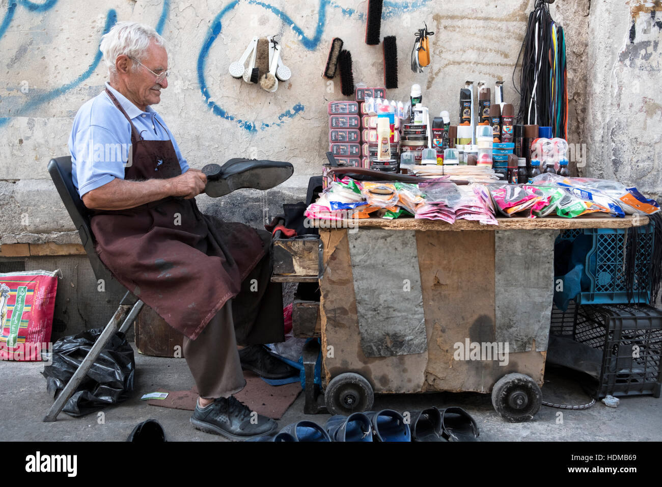 Un vendedor callejero repara zapatos en un establo en Teherán, de la provincia de Teherán, Irán. Foto de stock