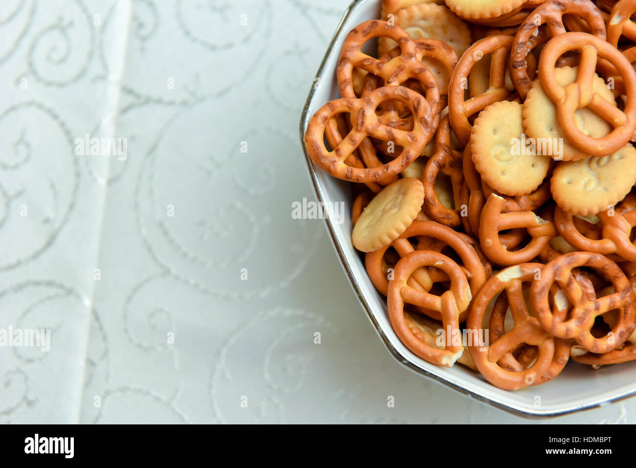 Recipiente con mini pretzels en la mesa de luz natural Foto de stock