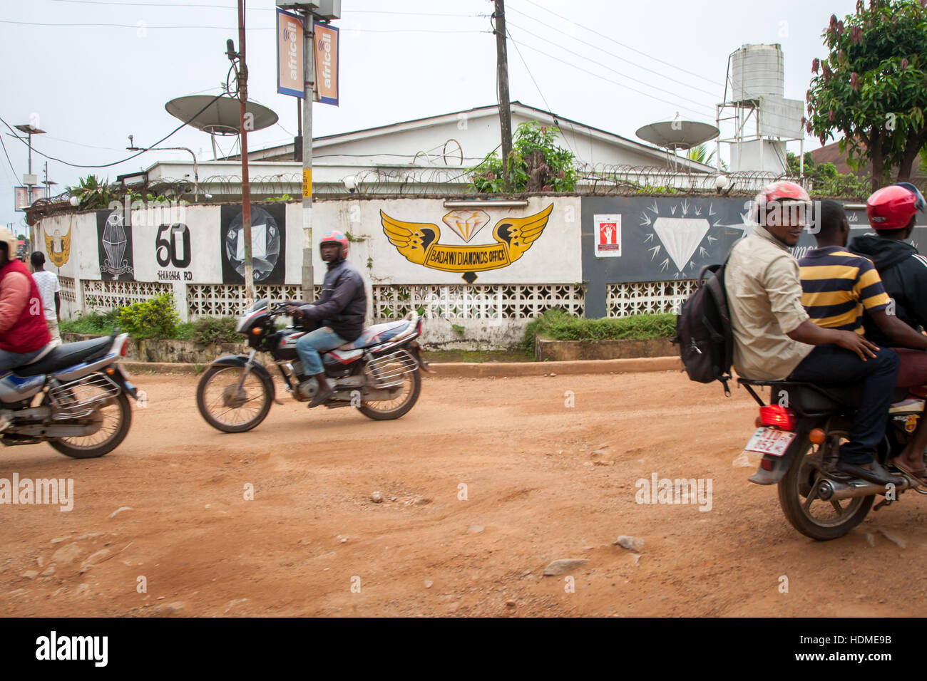 Okada (taxi) frente a la oficina de distribución de Diamons en Kenema, Sierra Leona. Estas antenas parabólicas sugieren relaciones comerciales internacionales Foto de stock
