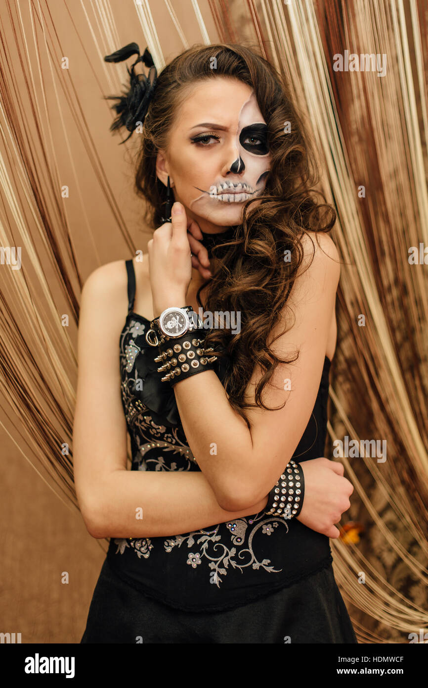 Mujer joven en negro con calavera media cara maquillaje Fotografía de stock  - Alamy