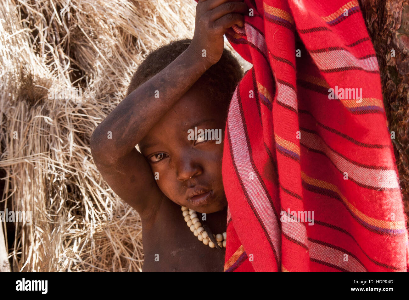 Curioso niño Hadzabe asomando de una manta, el lago Eyasi, Tanzania Foto de stock