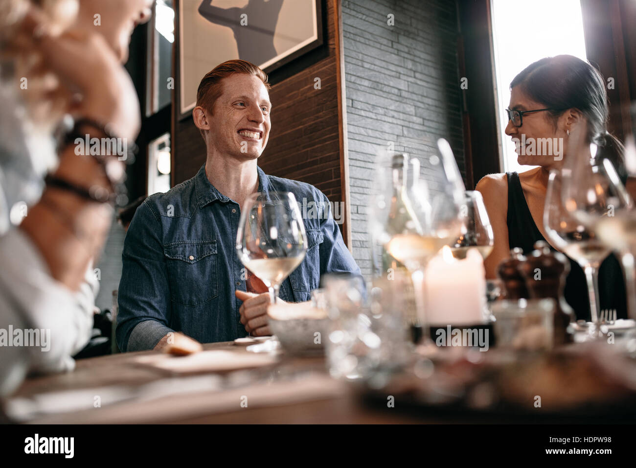 Feliz joven con amigos en el café. Los jóvenes de disfrutar de una cena en un restaurante. Foto de stock