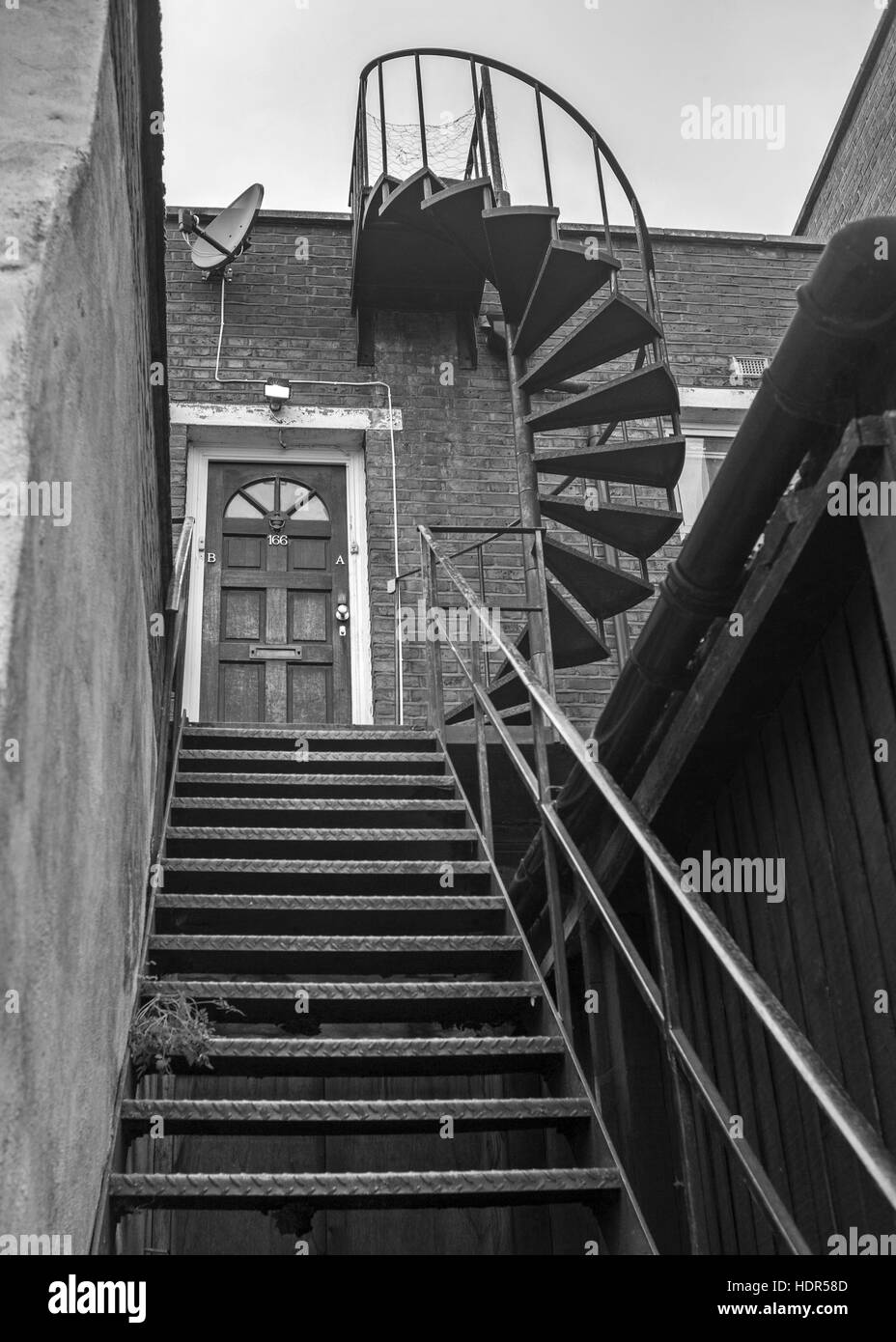 Escalera de hierro hasta la puerta con escalera de hierro en espiral hasta el techo Foto de stock