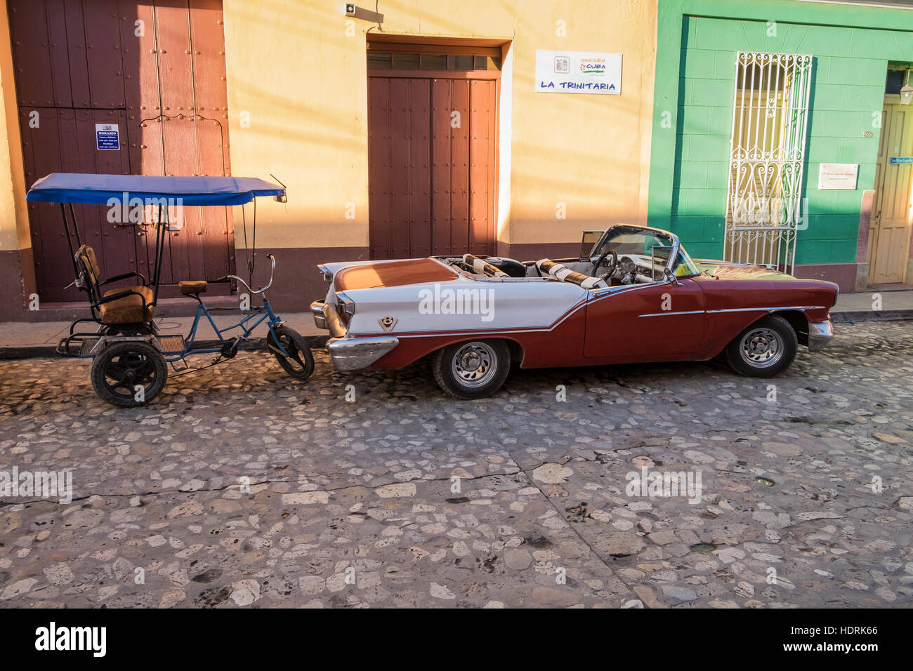 Cabriolet 1950 viejos coches americanos y triciclo taxi aparcado en la calle en Trinidad, Cuba Foto de stock