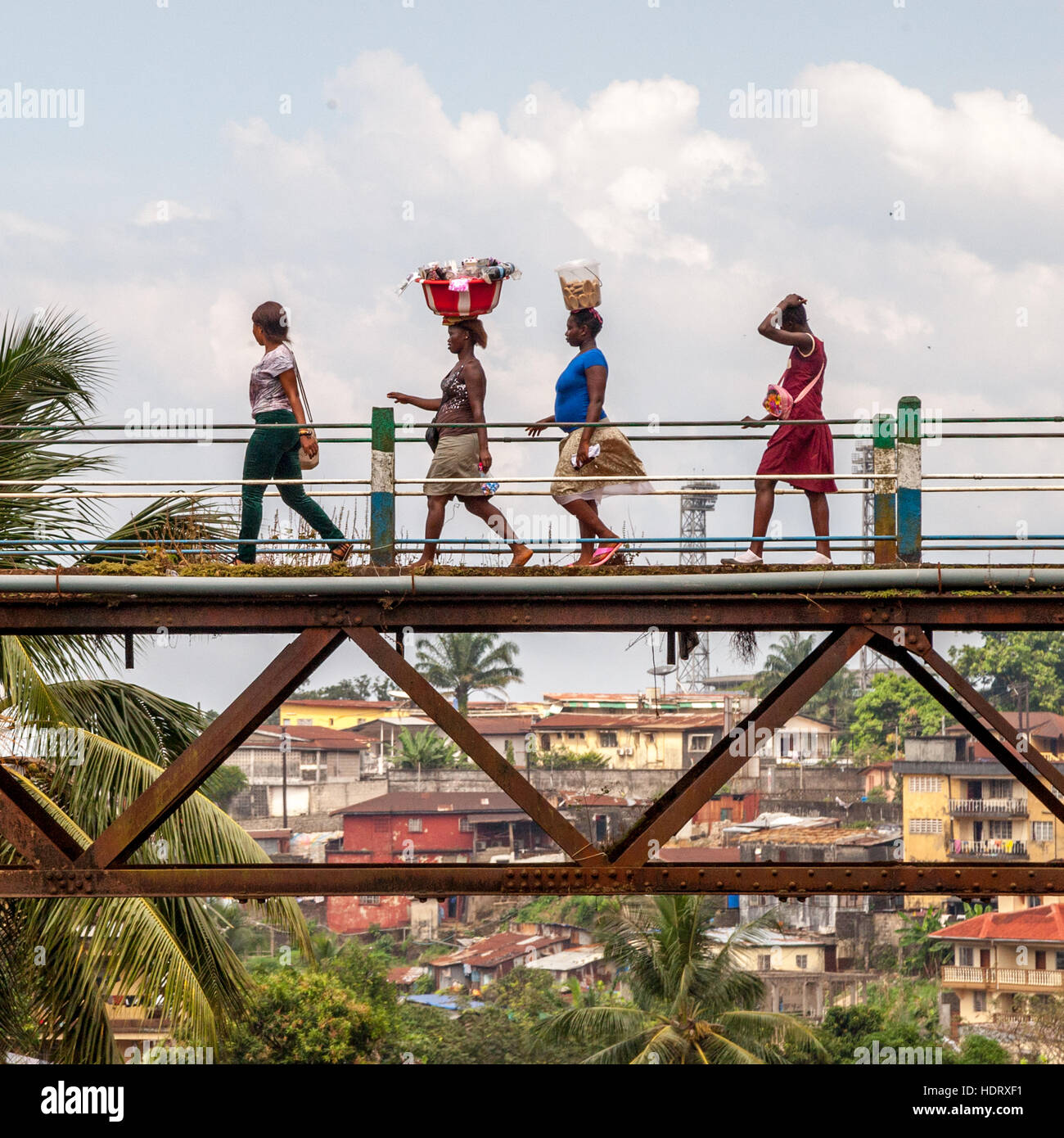 Mujeres que cruzan el viejo puente ferroviario de Freetown, el puente Tengbeh, llevando mercancías en la cabeza Foto de stock