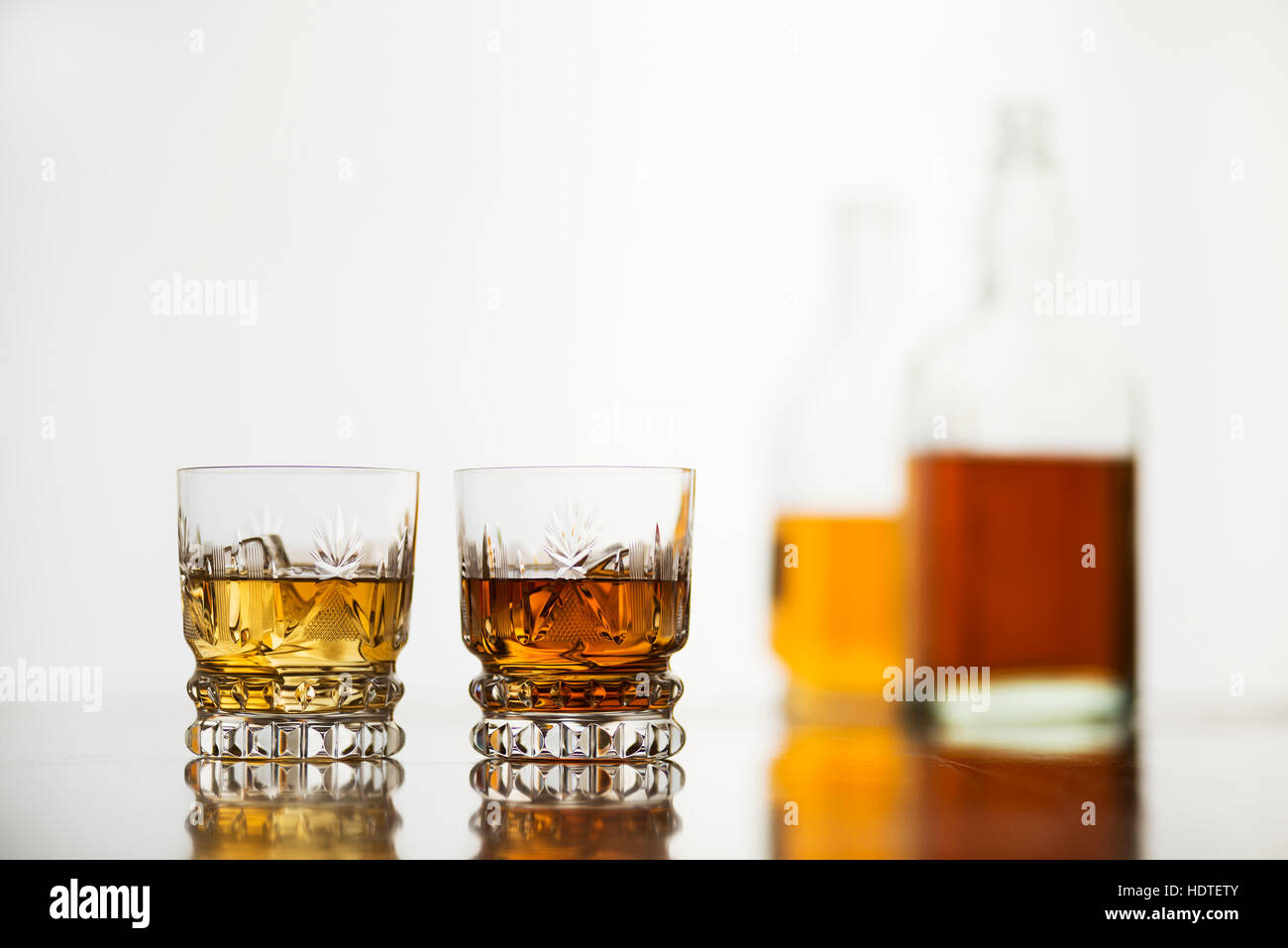 Gafas con botellas de whisky sobre fondo blanco. Foto de stock