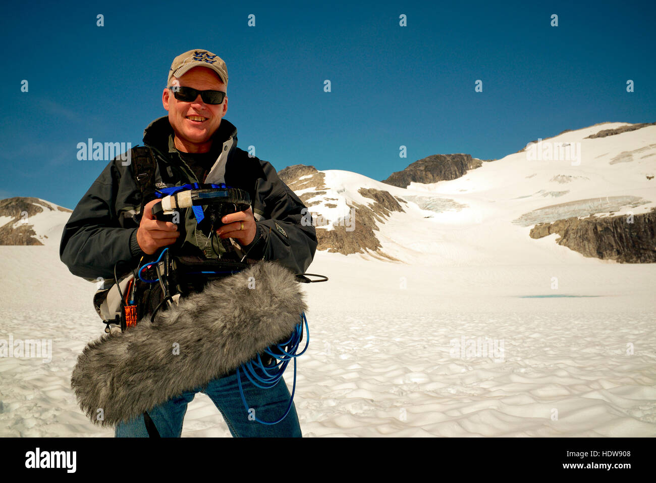 Paul Andrew Lawrence, mezclador de sonido de producción en Alaska trabajando en un comercial de disparar en la cima de un glaciar en el sureste de Alaska. Foto de stock