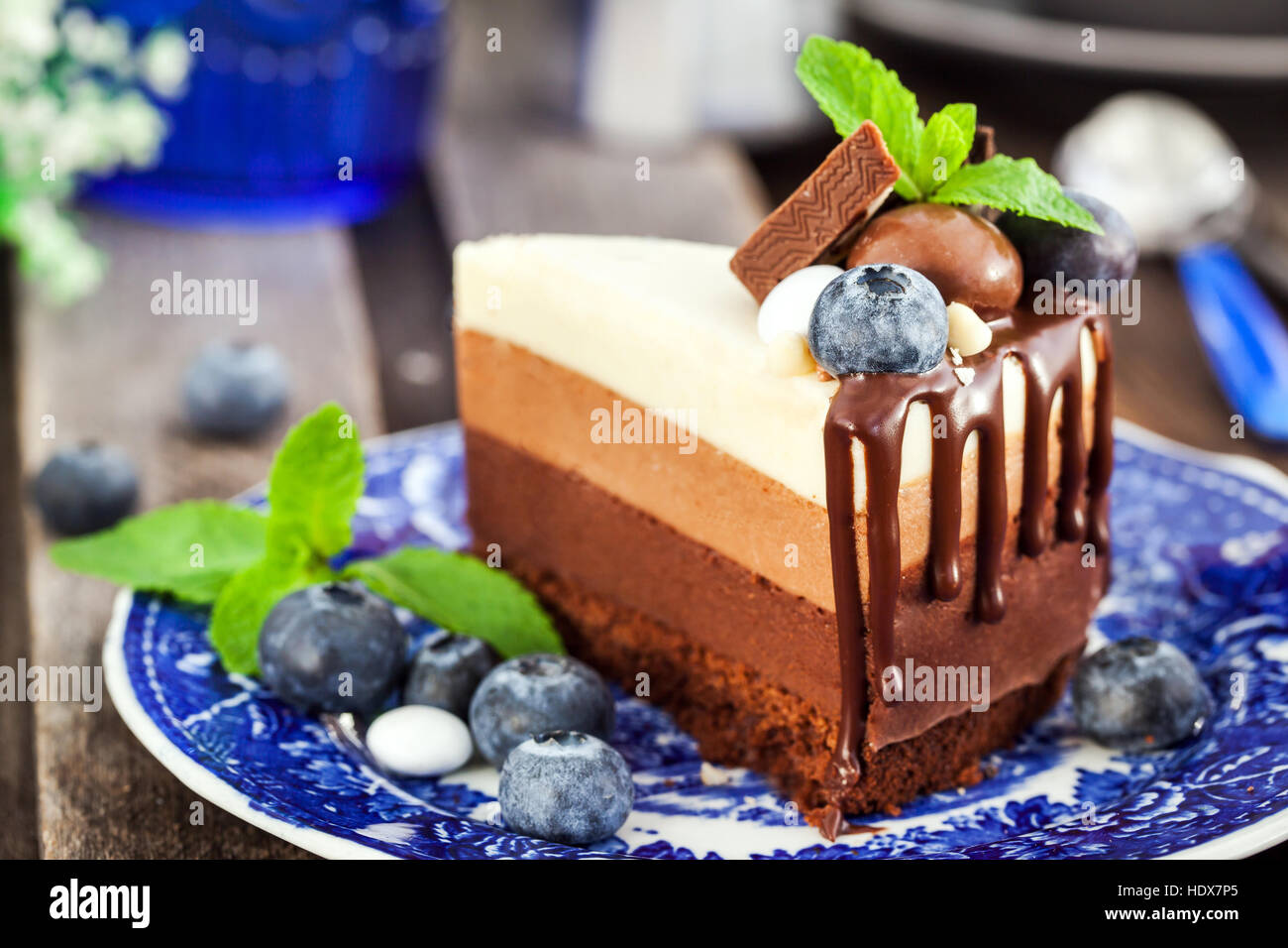 Trozo de pastel delicioso mousse de chocolate tres decorado con arándanos frescos, menta y dulces. Foto de stock