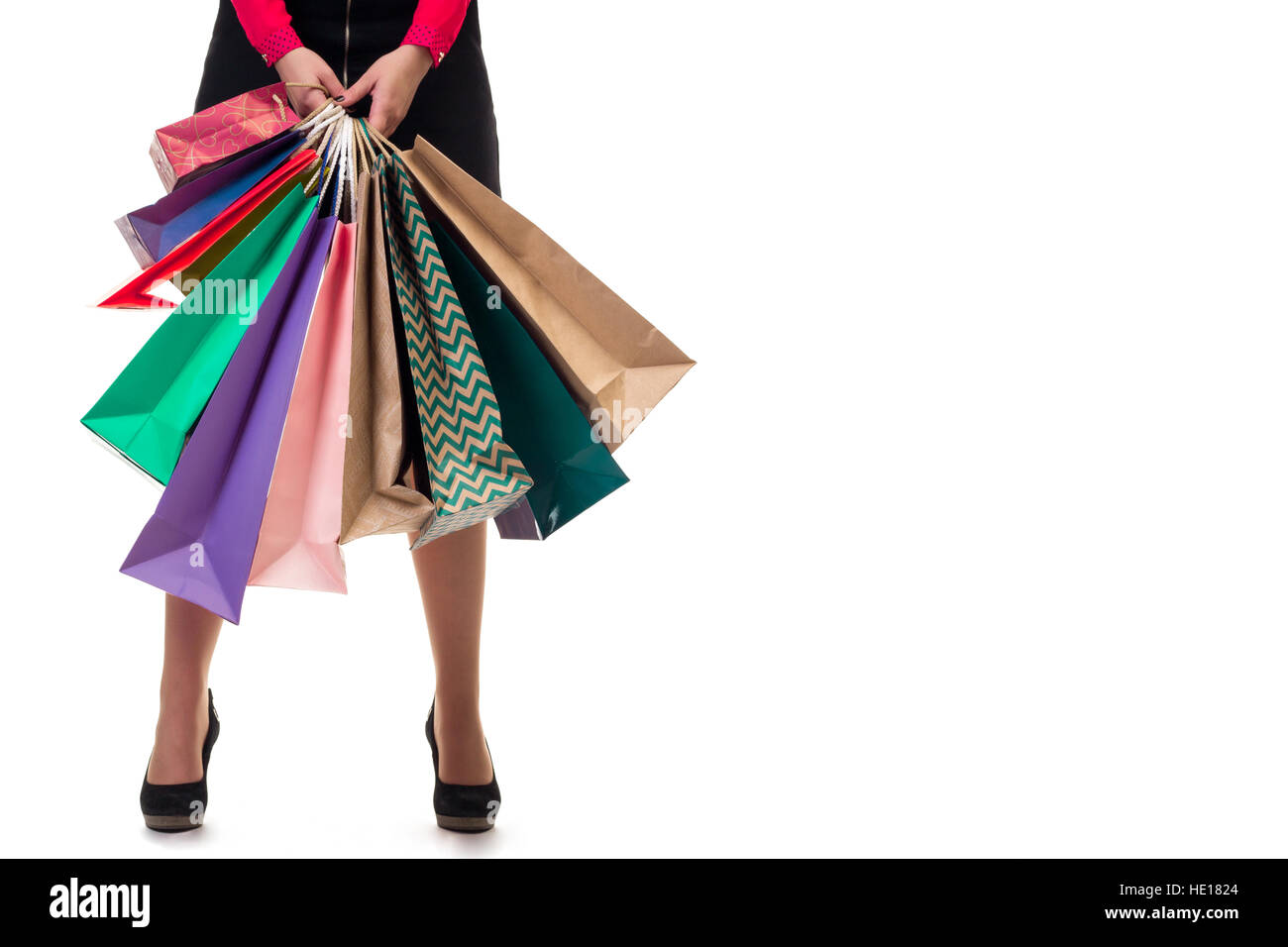 Cierre inferior de pie mujer vistiendo falda corta y zapatos con altos cerros multicolores holding bolsas de papel comercial y paquetes, aislado de Pentecostés Foto de stock