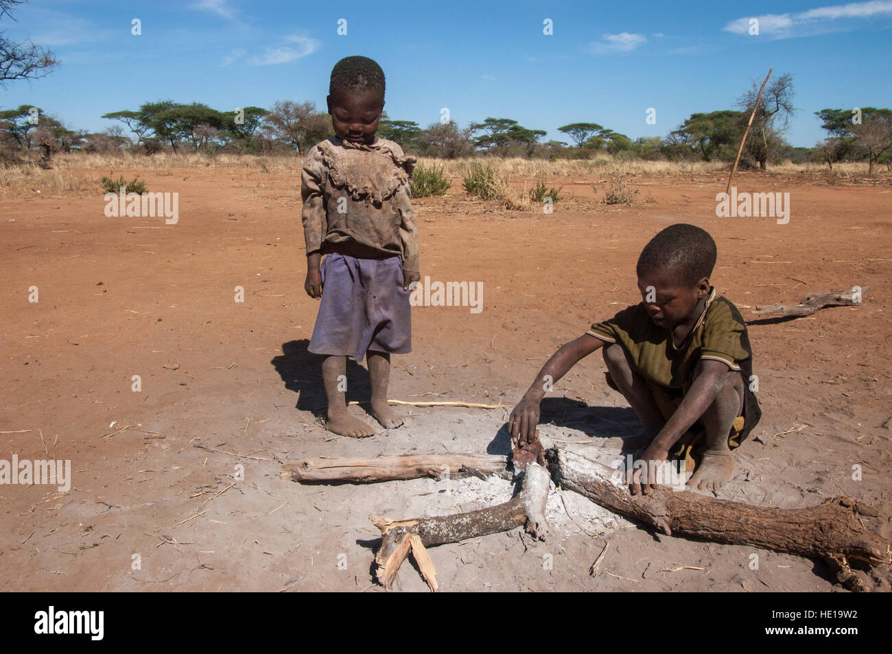 Dos hijos en el asentamiento permanente de la tribu Hadza iniciar un fuego abierto, Yaeda valle, región Manyara, Tanzania Foto de stock