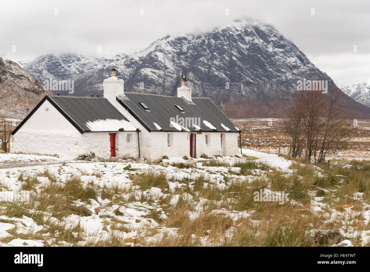 Casa tradicional escocesa por la avenida West Highland Way acera en Rannoch Moor, Glencoe temprano en el invierno la nieve. Escocia, Reino Unido Foto de stock