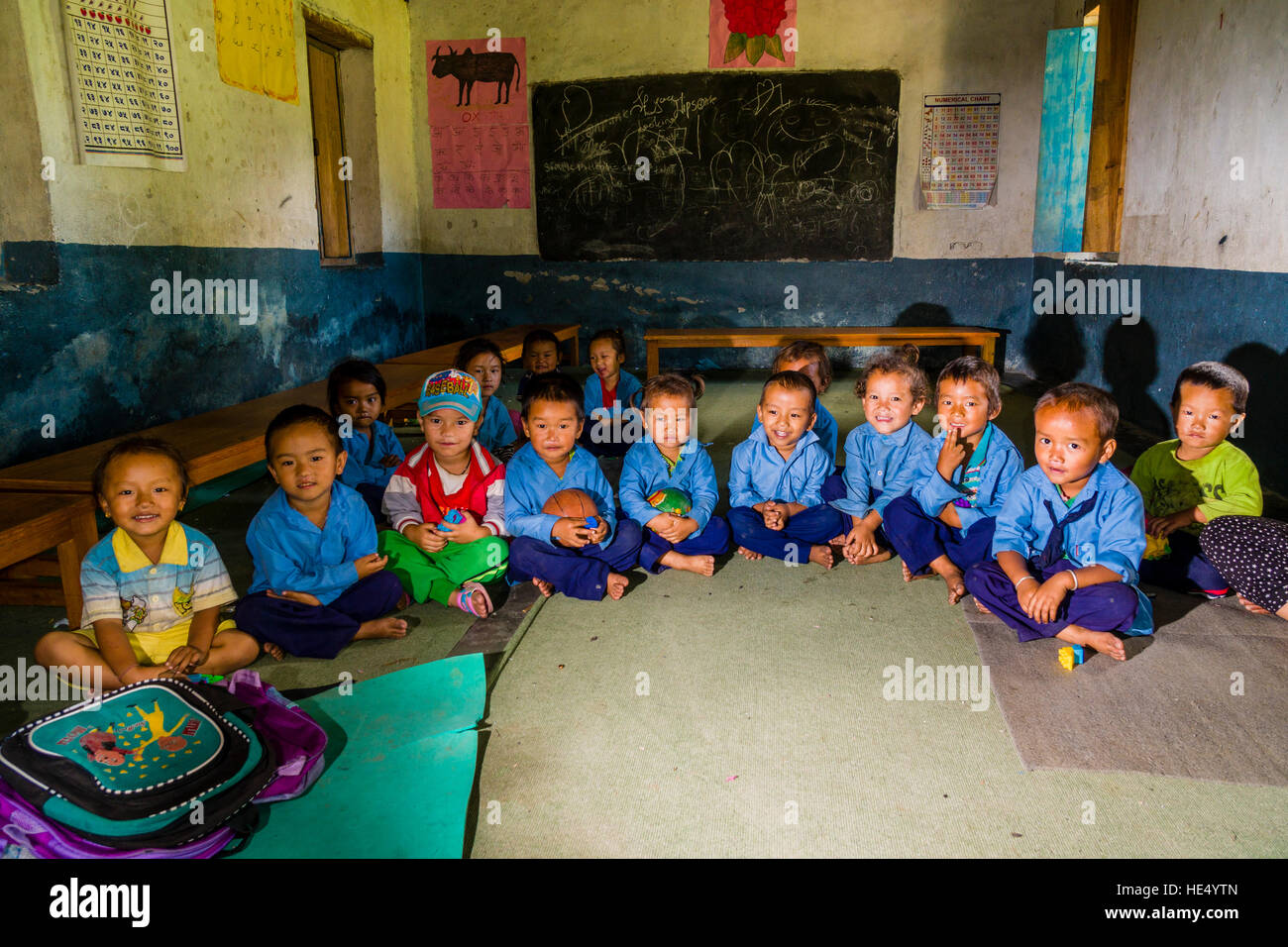 Un grupo de niños vestidos de azul está sentado en un círculo en el jardín de infantes local Foto de stock