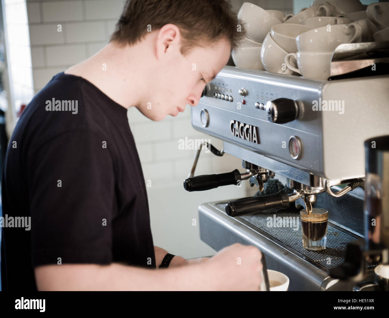 Camarero haciendo un café espresso en una cafetería concurrida Foto de stock