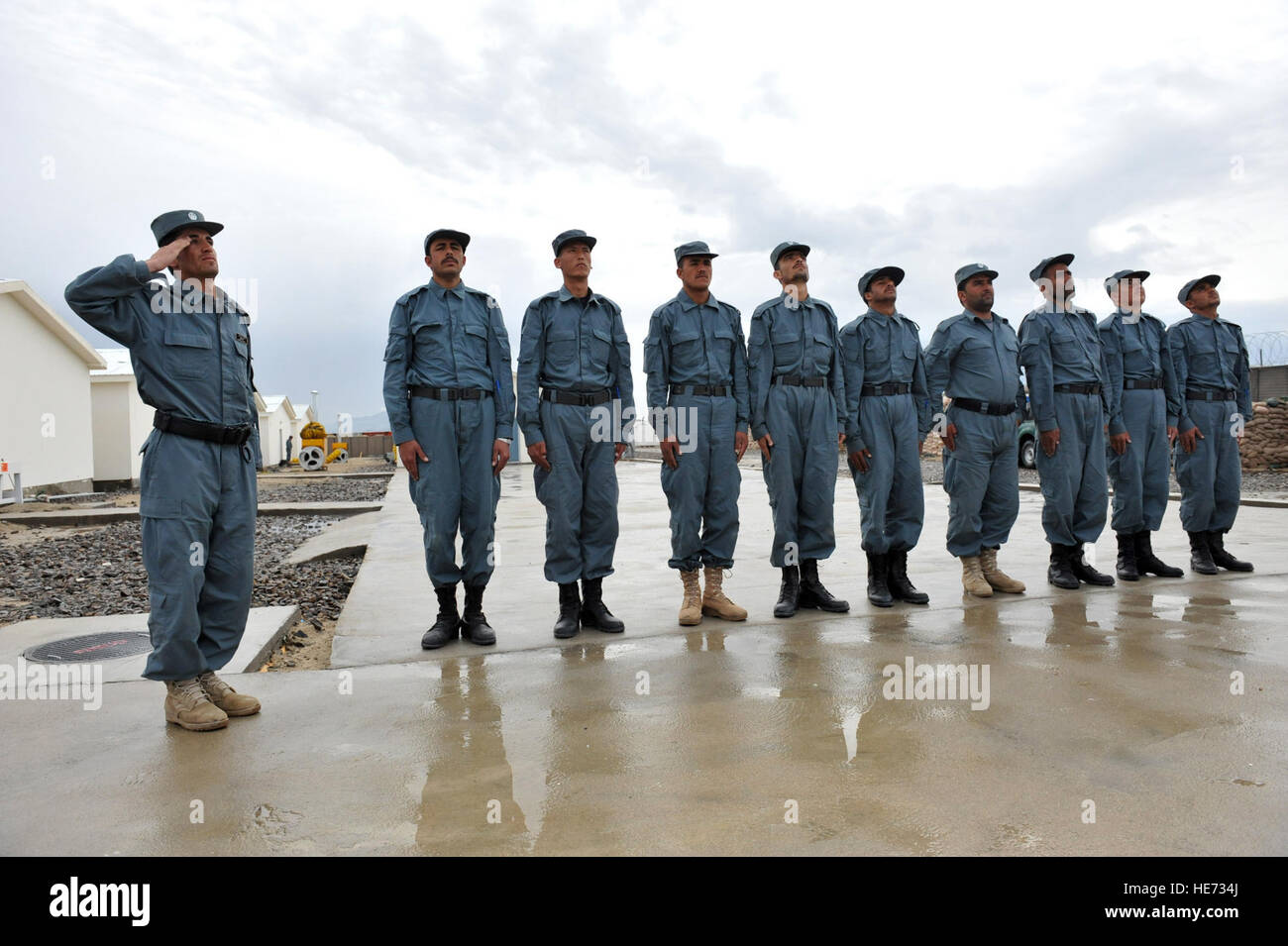 Un oficial de la policía nacional afgana saluda, como la bandera de