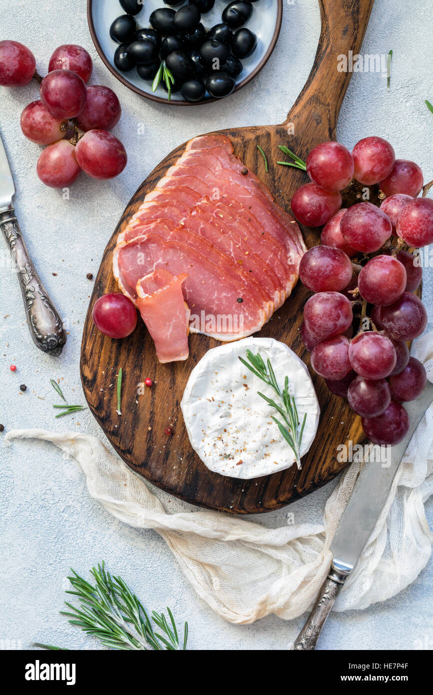 Charola con carne, uvas, queso y aceitunas. Entremeses o tapas. Vista superior Foto de stock