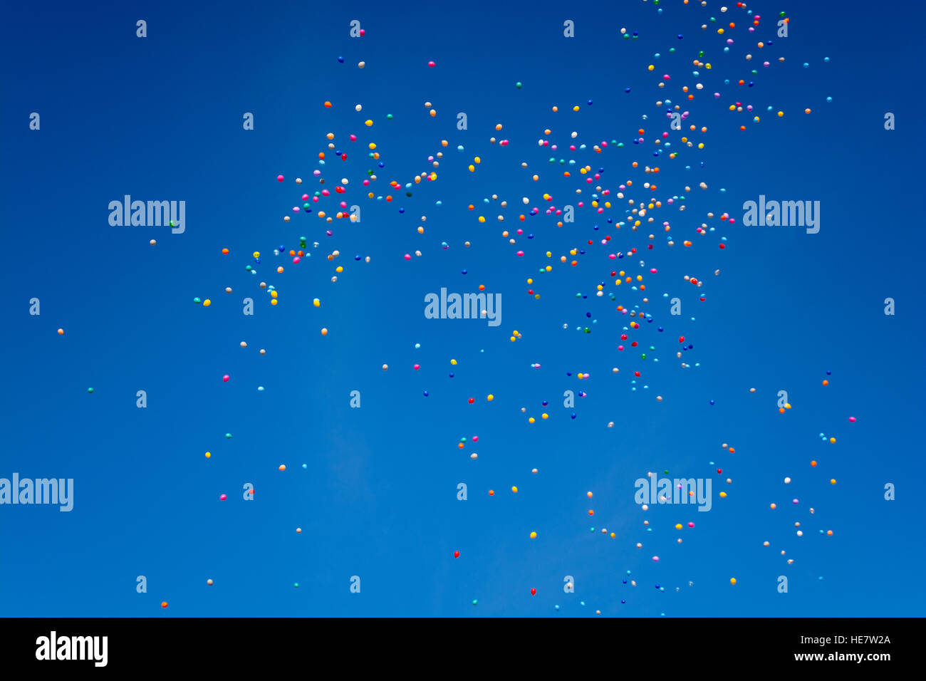 Cientos de globos de colores vuelan por el diáfano cielo azul Foto de stock