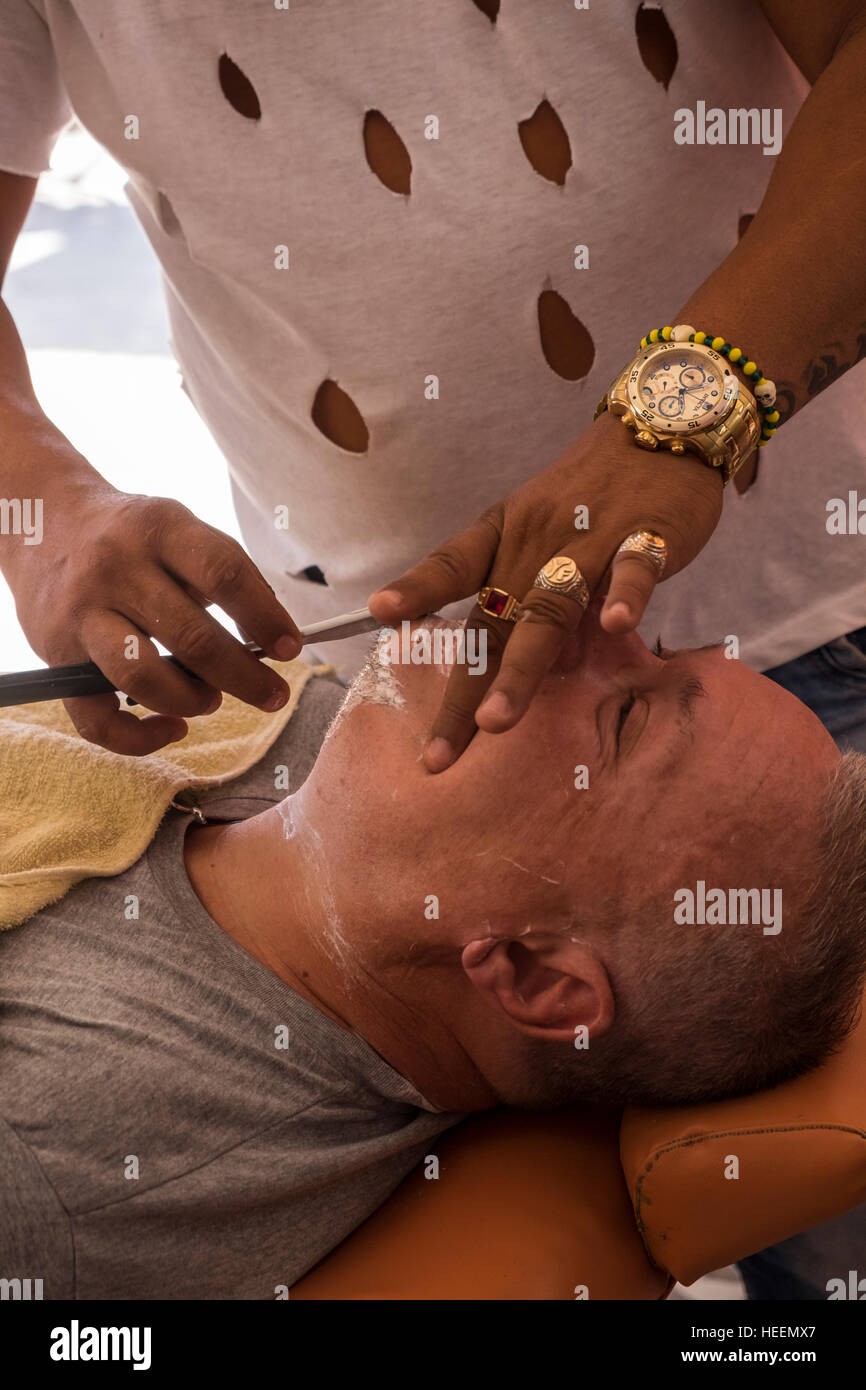 El hombre tiene un afeitado en una tienda de peluqueros, Trinidad, Cuba Foto de stock