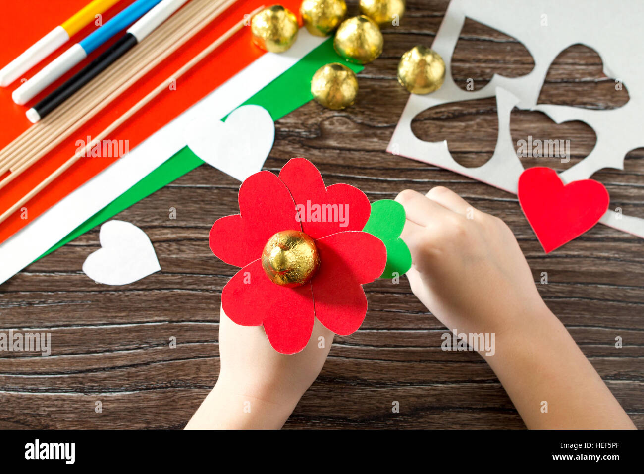 Regalo para niños. Corazón un ramo de flores hechas de papel y dulces en el  día de San Valentín. Children's art project, una artesanía para niños.  Hechos a mano Fotografía de stock -