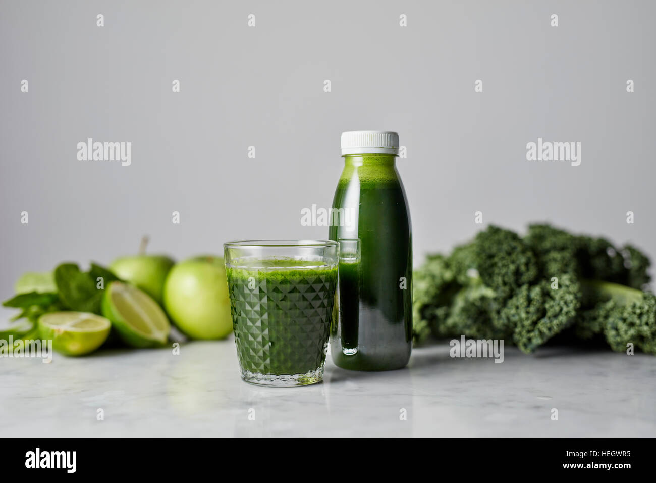 La col rizada verde fresco jugo de manzana orgánica saludable vitaminas kale lime vaso para beber una botella plástica Foto de stock