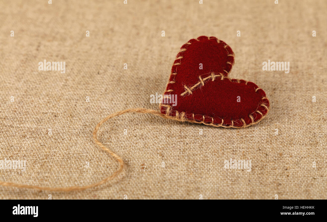 El Día de San Valentín, una plantilla a mano Fieltro marrón craft juguete cosidos con hilo de yute rosca corazón sobre lienzo de lino, de cerca, un alto ángulo de visualización Foto de stock