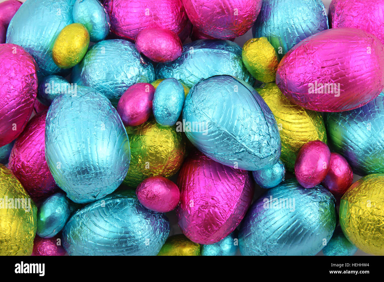 Montón de lámina de huevos de pascua de chocolate envuelto en rosa, azul y verde lima. Foto de stock