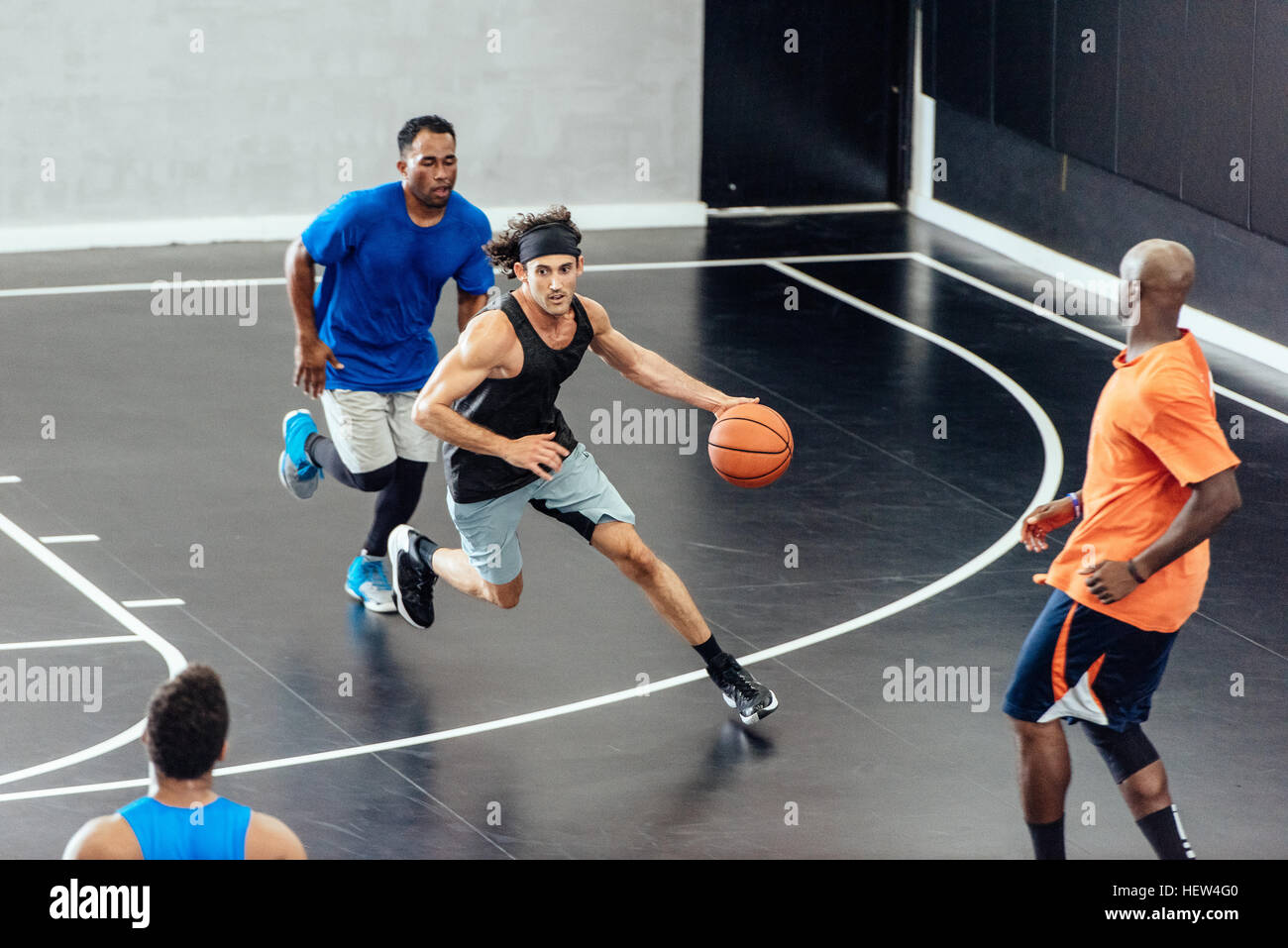 Jugadores de baloncesto masculino corriendo con el balón y defender en la cancha de baloncesto Foto de stock