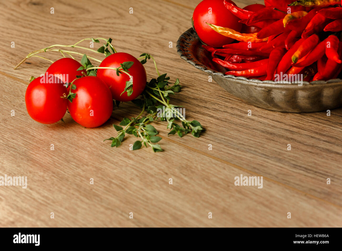 Tomates cherry,tomillo y pimientos rojos sobre fondo de madera Foto de stock