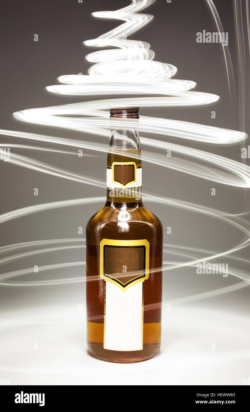 Composición conceptual de bebidas alcohólicas, llena la botella de brandy y efectos de iluminación. Foto de stock