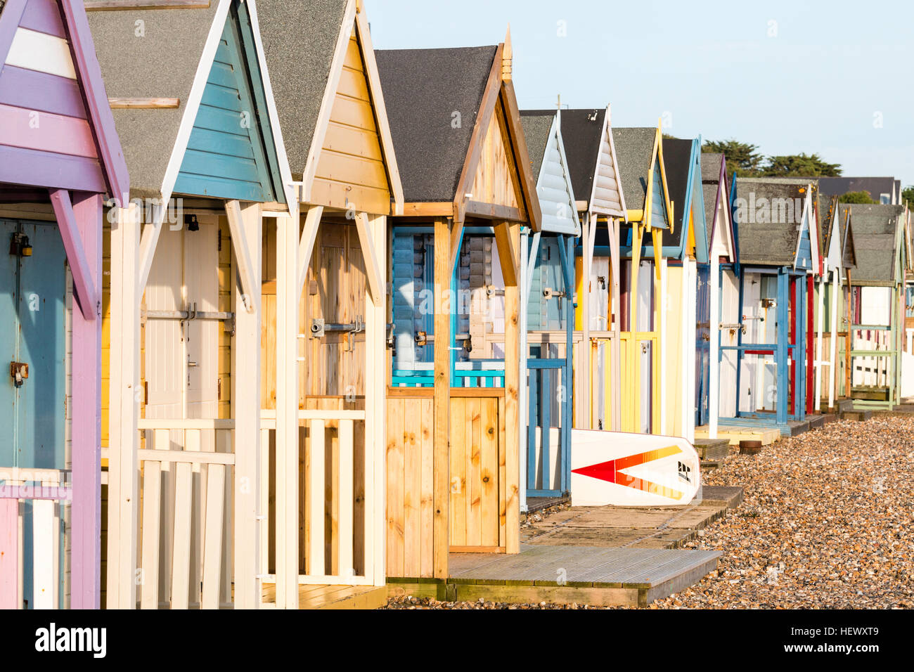 Vista a lo largo de la fila de Inglés tradicional cabañas de playa en Herne Bay, en la costa de Kent. Pintado en diversos principalmente los tonos pastel. Temprano en la mañana. Foto de stock