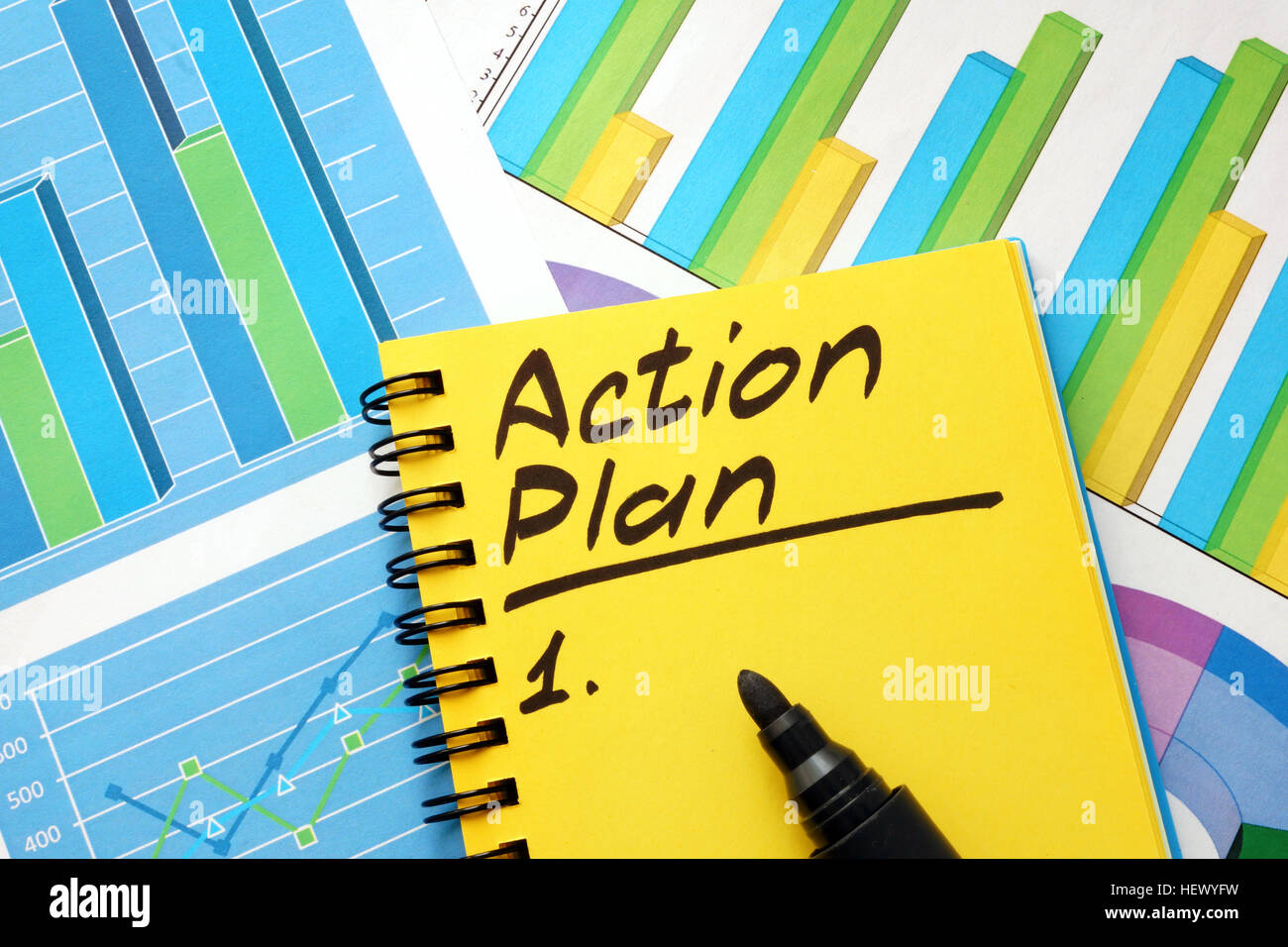 Lista de plan de acción en una nota y gráficos financieros. Foto de stock
