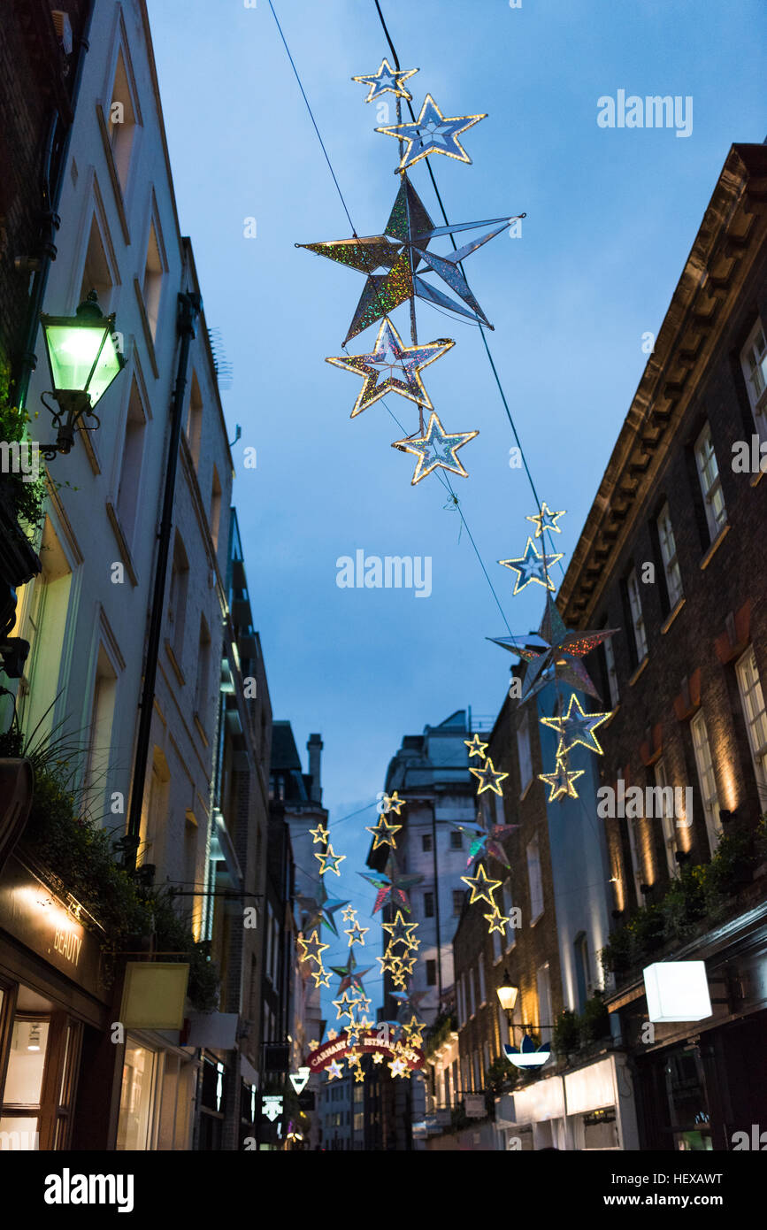 Forma de estrella decoraciones de Navidad por encima de las calles de la ciudad al atardecer, Londres, Reino Unido. Foto de stock