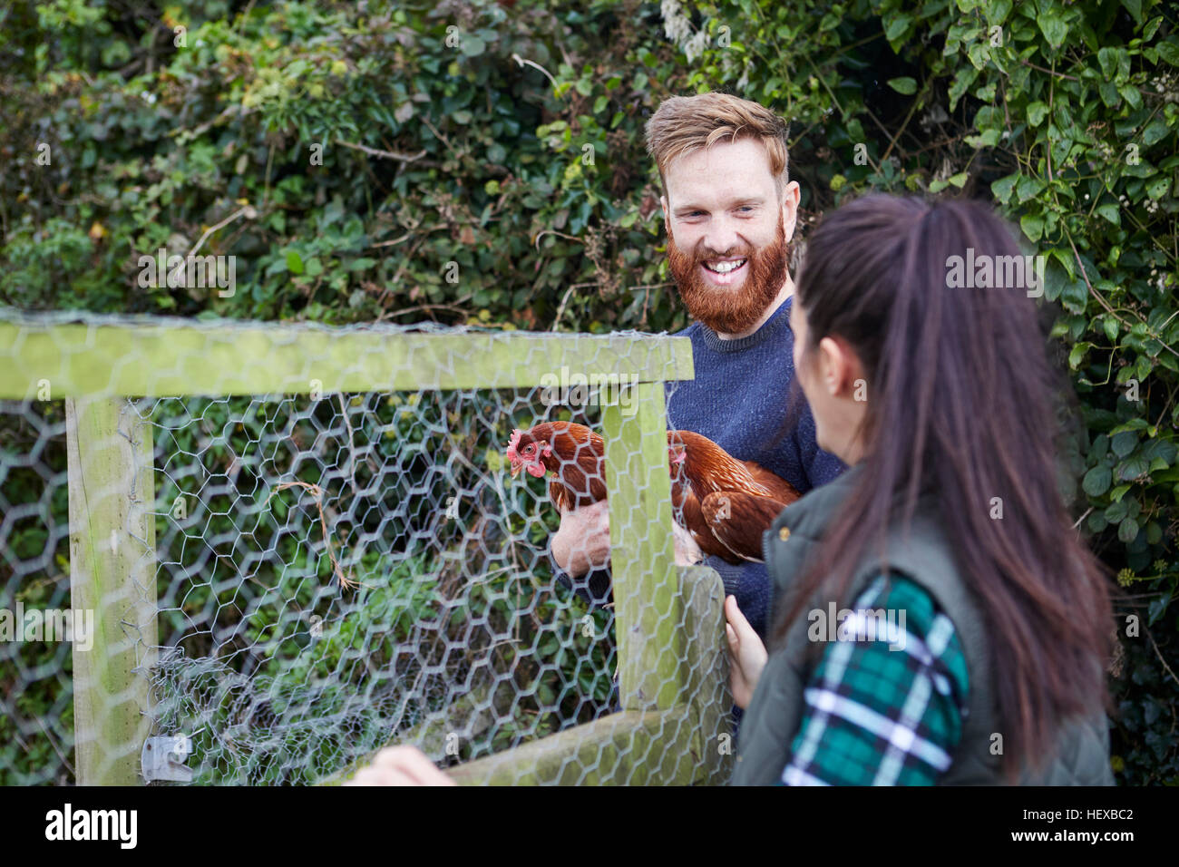 Pareja joven en granja avícola sosteniendo los pollos Foto de stock