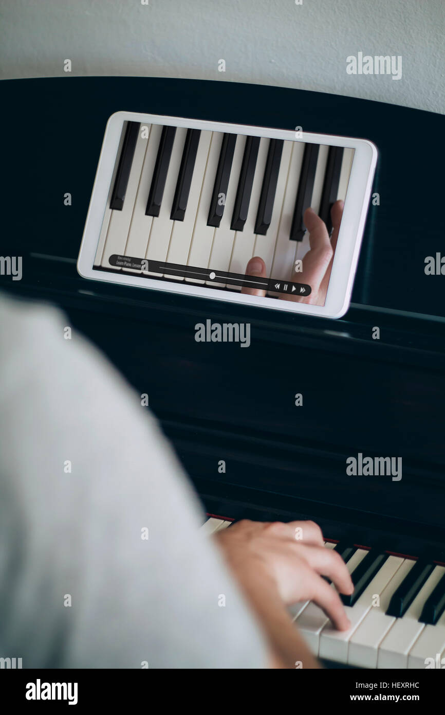 Aprendizaje hombre tocando el piano con video tutorial en un tablet  Fotografía de stock - Alamy