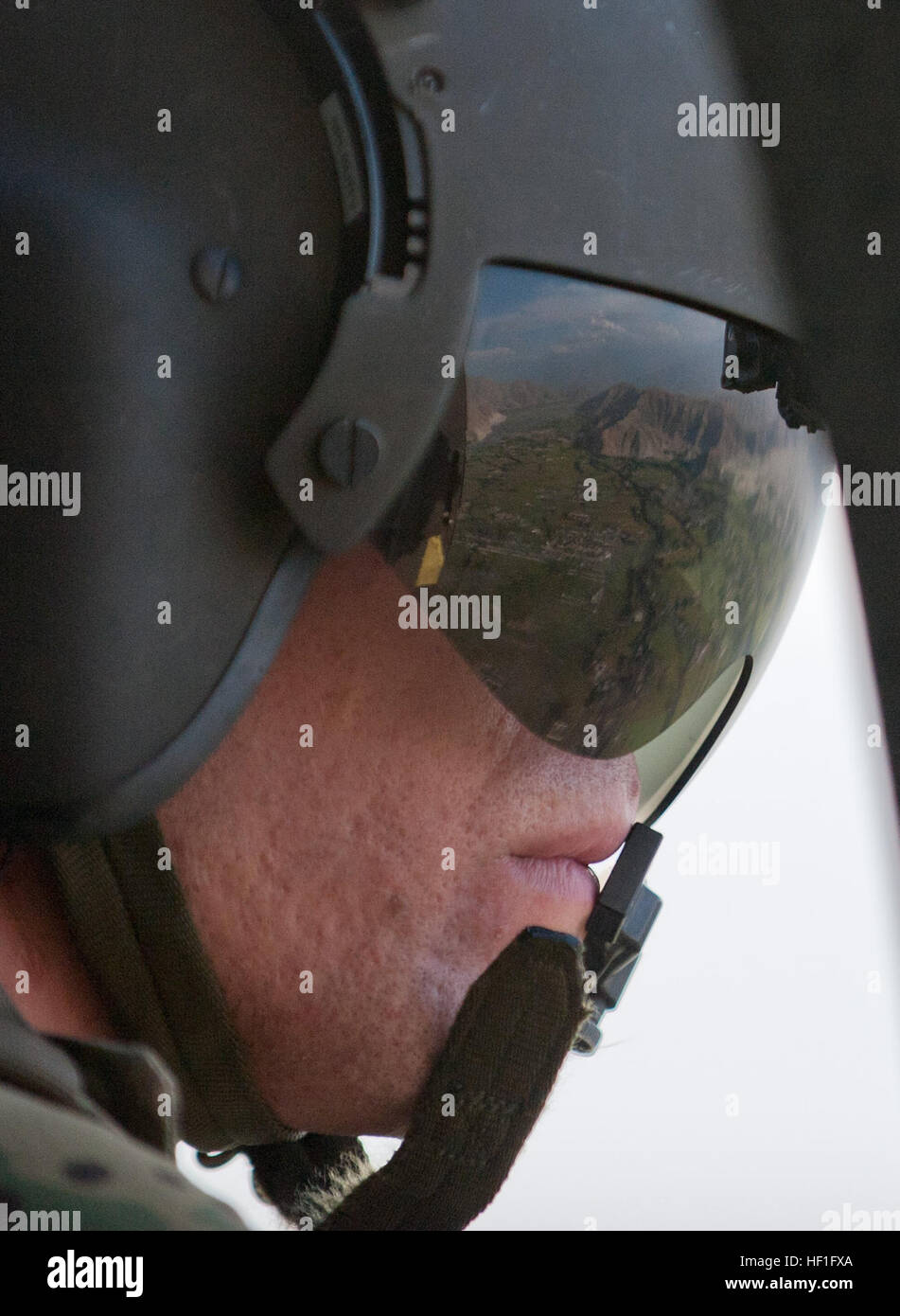 Una vista aérea de Jalalabad se refleja en la visera del U.S. Army Spc. Trevor Milbury, un jefe de la tripulación con el pelotón Dustoff Medevac, Compañía Charlie, 3er Batallón, 238ª Regimiento de Aviación, Task Force Dragon, durante un ejercicio de entrenamiento de la grúa en un helicóptero UH-60 Blackhawk cerca de la base de operaciones avanzada Fenty, provincia de Nangarhar, Afganistán, el 16 de septiembre de 2013. Equipos de evacuación médica proporcionado atención de urgencia a las fuerzas estadounidenses y de la Coalición, y transporte de pacientes por aire para instalaciones de atención médica. Utilizando un polipasto permite medevac tripulaciones para subir y bajar de suministros y personal en áreas remotas o traicionero whe Foto de stock