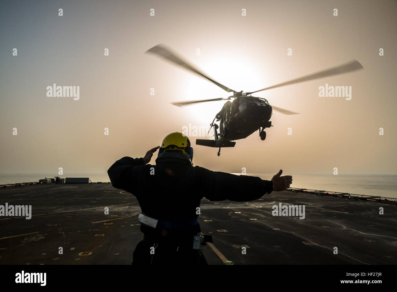 Petty Officer Ian Walker, una baraja de la mano en la RFA Cardigan Bay, auxiliar de la flota Real, la Marina Real del Reino Unido, da la señal para levantar a una evacuación médica UH-60 Black Hawk volados por los pilotos del 1er Batallón del 214Air Ambulance, 42ª Brigada de Aviación de Combate (Cabina) del Ejército de Estados Unidos, el 8 de junio de 2014, en algún lugar en el Golfo Arábigo. Los pilotos entrenados en la cubierta de los desembarques durante el ejercicio Kopis espartano, un intercambio entre el Cardigan Bay y tanto el Black Hawk y Apache AH-64 elementos de la cabina, 42 de la Guardia Nacional del Ejército de Nueva York. Spartan Kopis era la primera vez que American Apaches trabajó con un real Foto de stock