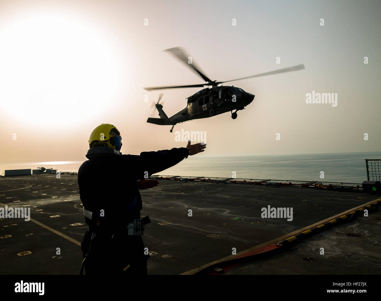 Petty Officer Ian Walker, una baraja de la mano en la RFA Cardigan Bay, auxiliar de la flota Real, la Marina Real del Reino Unido, da la señal para levantar a una evacuación médica UH-60 Black Hawk volados por los pilotos del 1er Batallón del 214Air Ambulance, 42ª Brigada de Aviación de Combate (Cabina) del Ejército de Estados Unidos, el 8 de junio de 2014, en algún lugar en el Golfo Arábigo. Los pilotos entrenados en la cubierta de los desembarques durante el ejercicio Kopis espartano, un intercambio entre el Cardigan Bay y tanto el Black Hawk y Apache AH-64 elementos de la cabina, 42 de la Guardia Nacional del Ejército de Nueva York. Spartan Kopis era la primera vez que American Apaches trabajó con un real Foto de stock