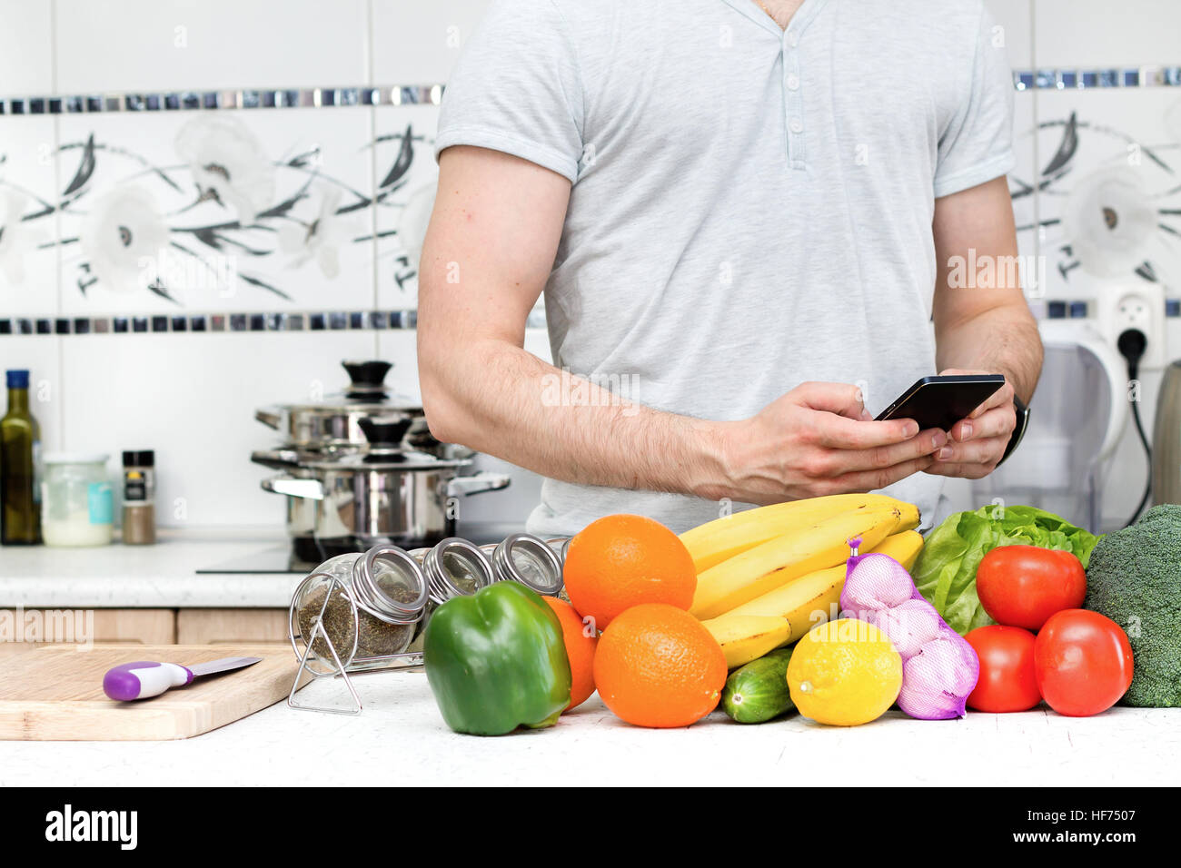 Usando el smartphone a la cocina por hombre saludable Foto de stock